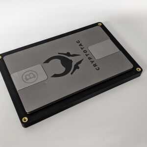 Open black The Tomb holder with a CRYPTOTAG metal Bitcoin seed backup on a white surface