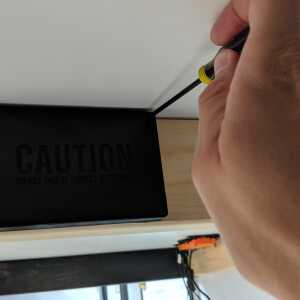 Securing the cover on The Tomb hidden Bitcoin seed plate wall mount with a screwdriver