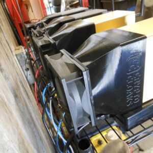 Row of equipment on a wire shelf with dark tapered shrouds and exposed fan blades in the foreground.
