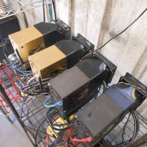 Overhead view of a wire rack holding several equipment units with dark fan shrouds and multicolored cables.