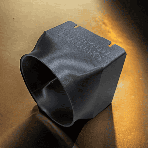Black circular-mouth shroud with a rectangular body and internal divider on a warm-toned surface.
