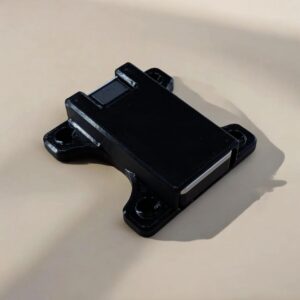 Three-quarter view of a black Jade Plus hardware wallet mount holding the device with four projecting mounting tabs