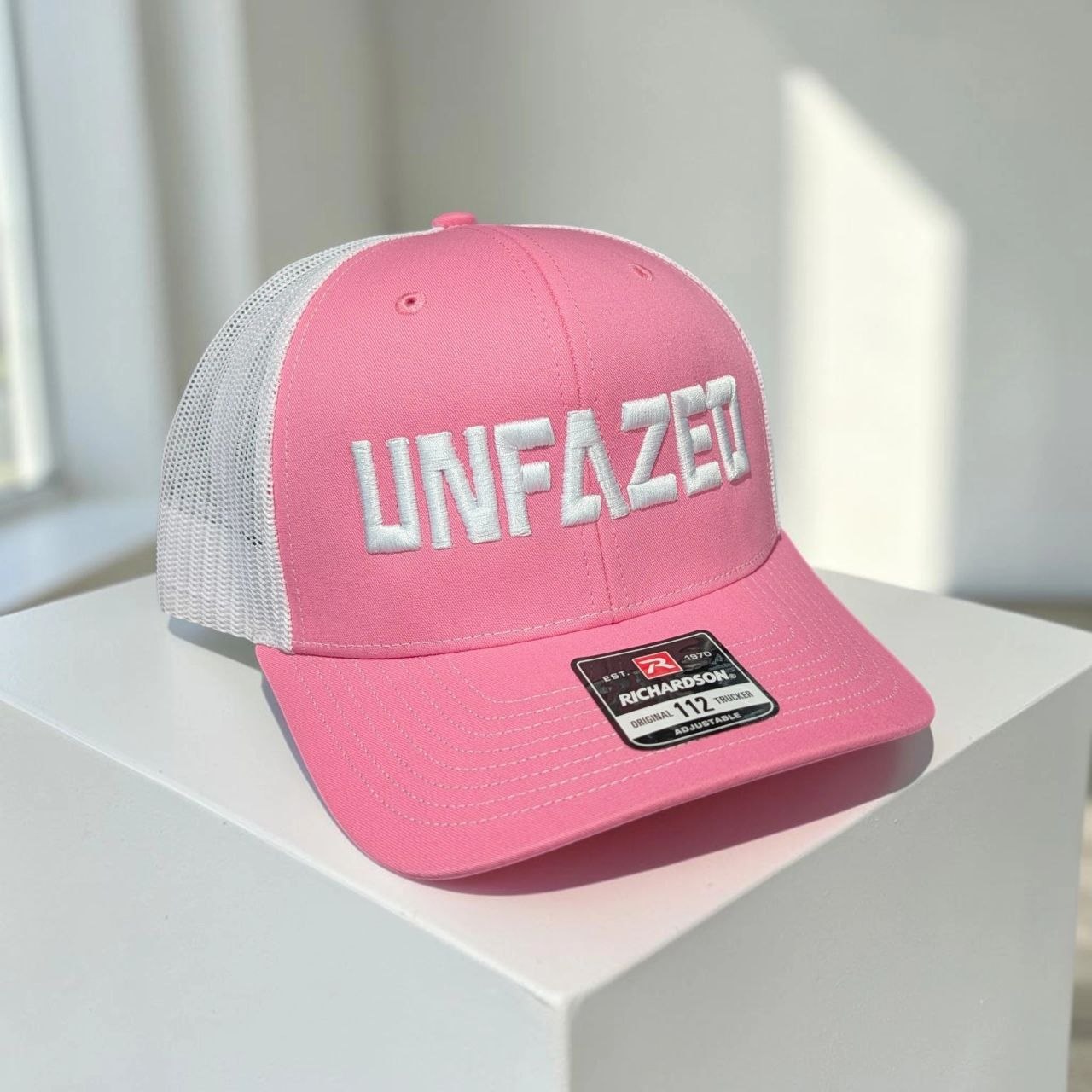 Pink and white UNFAZED Richardson 112 trucker hat, pink front and brim with white mesh back